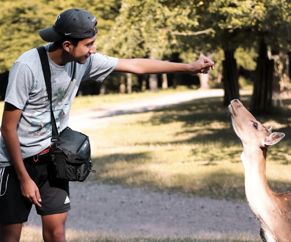 man in gray and black jacket and black shorts holding brown short coated dog