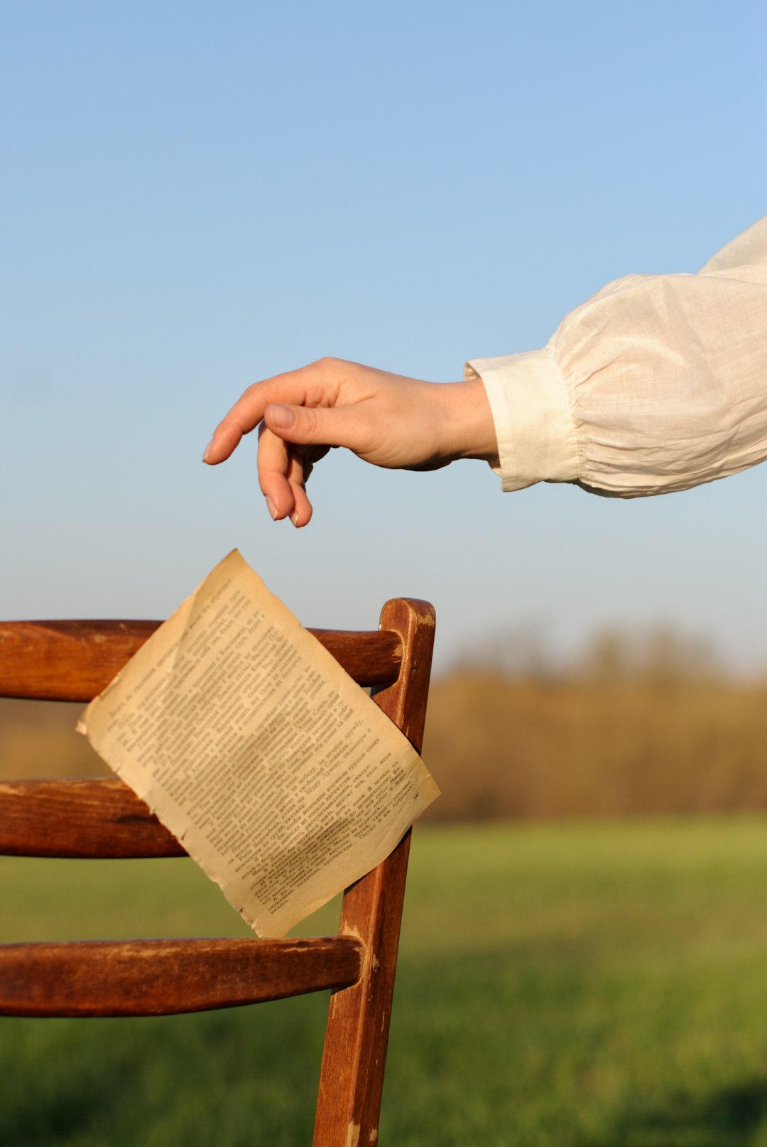 person in white long sleeve shirt holding brown wooden chair