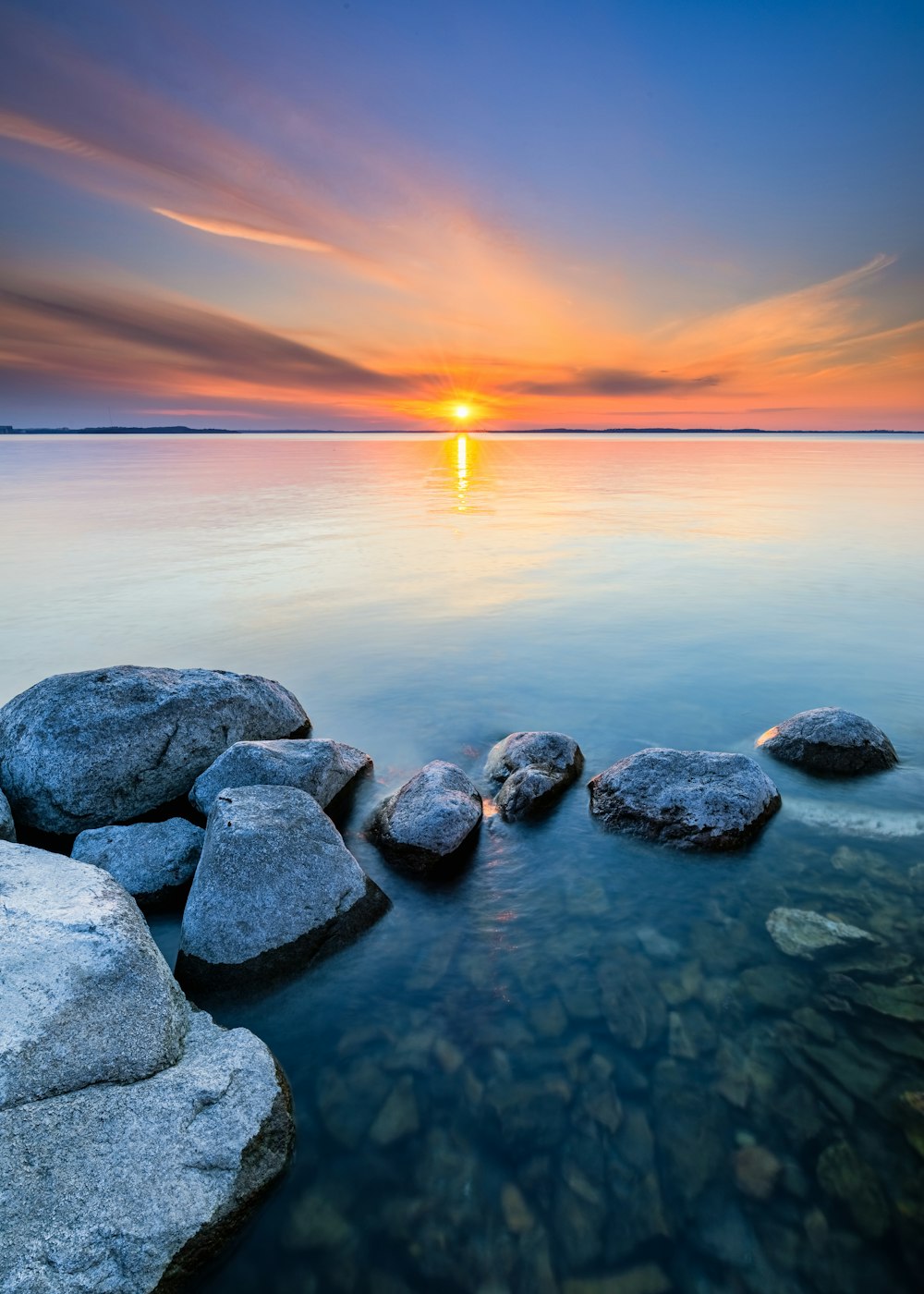 roches grises sur le plan d’eau au coucher du soleil