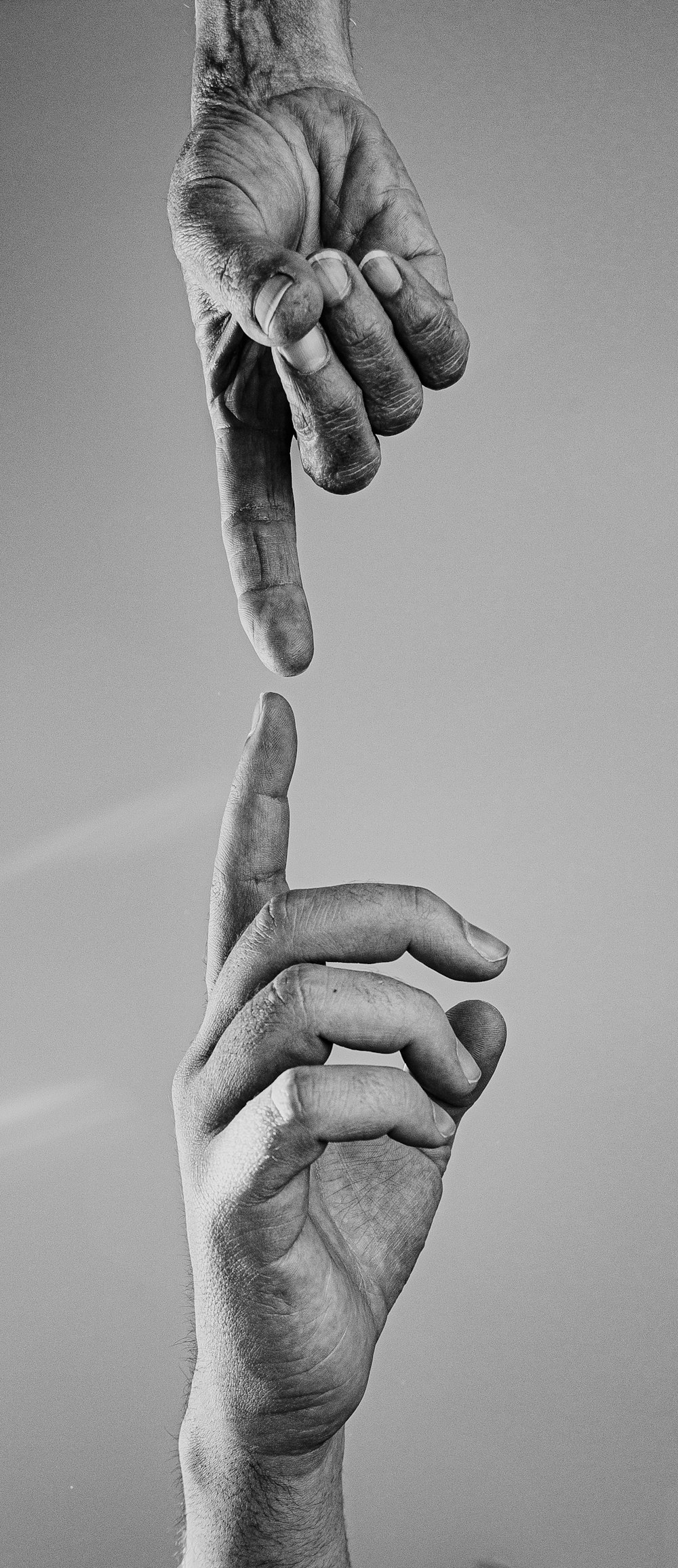 a black and white photo of two hands reaching for each other