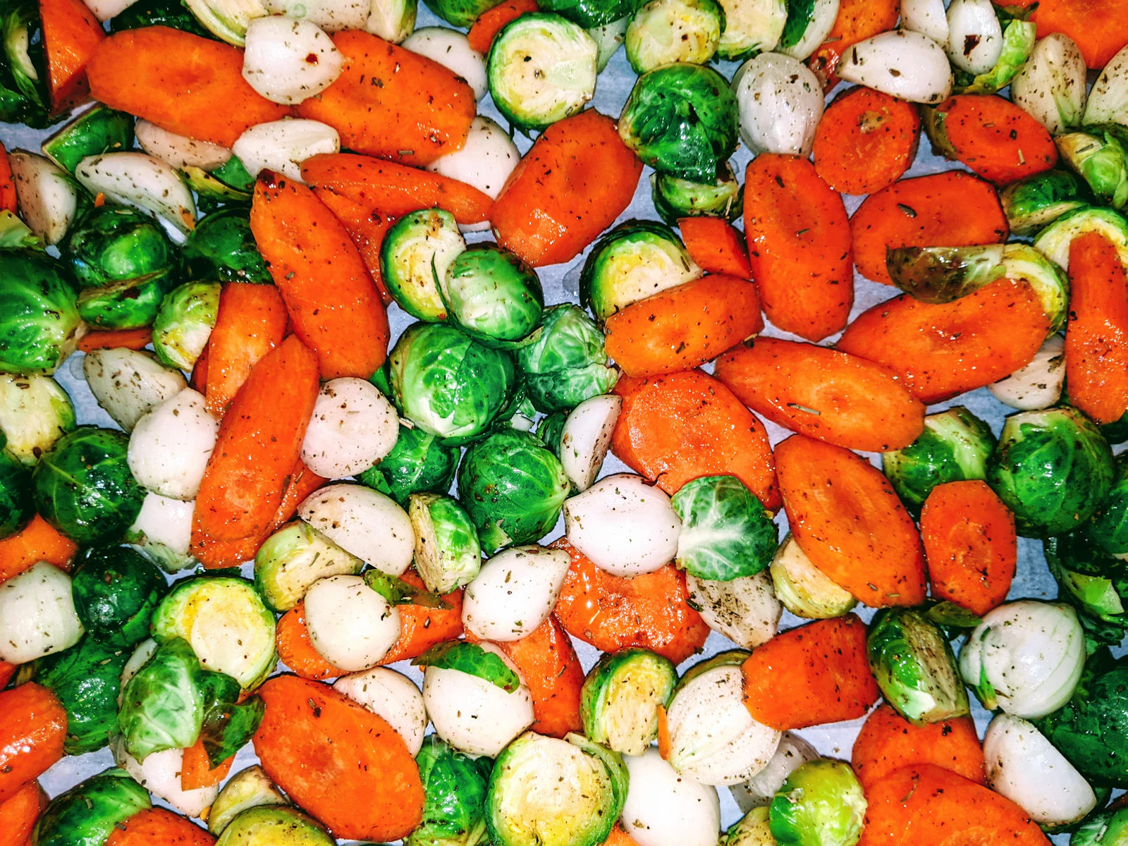 Plaque de légumes rôtis colorés : carottes, choux de Bruxelles et oignons