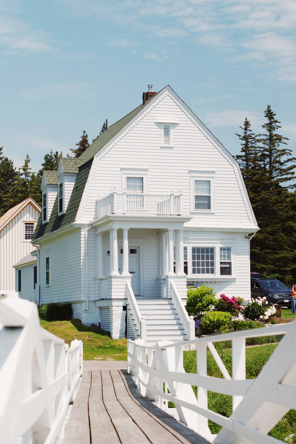 white wooden house near green trees under blue sky during daytime