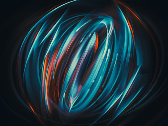 An abstract image featuring swirling, dynamic light trails in vivid colors against a dark background. The motion creates a sense of fluidity and energy, with dominant hues of teal and orange, interwoven to form an intricate circular pattern.