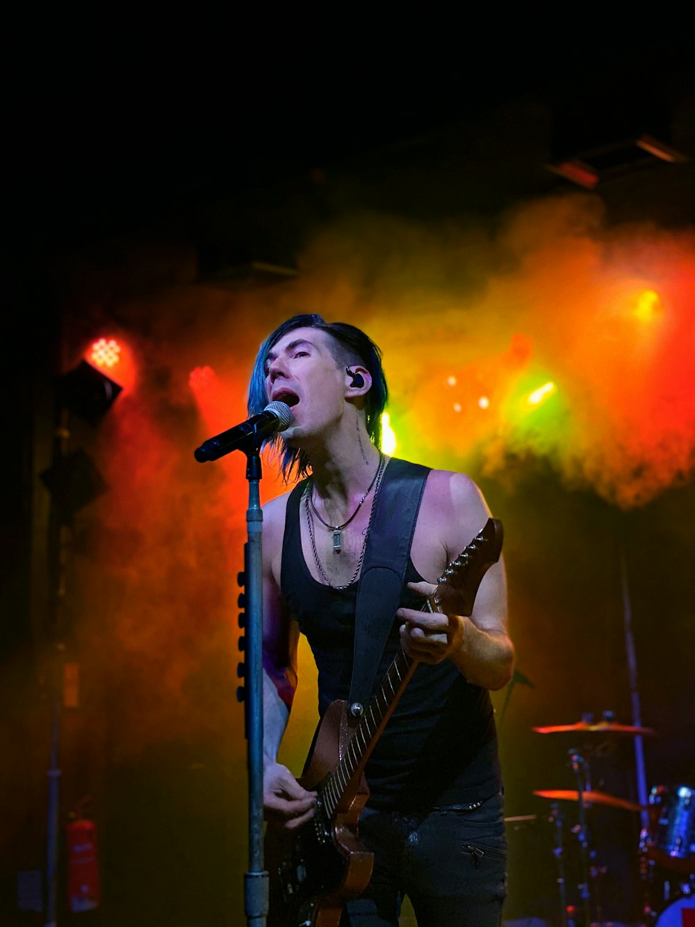 man in black vest singing on stage
