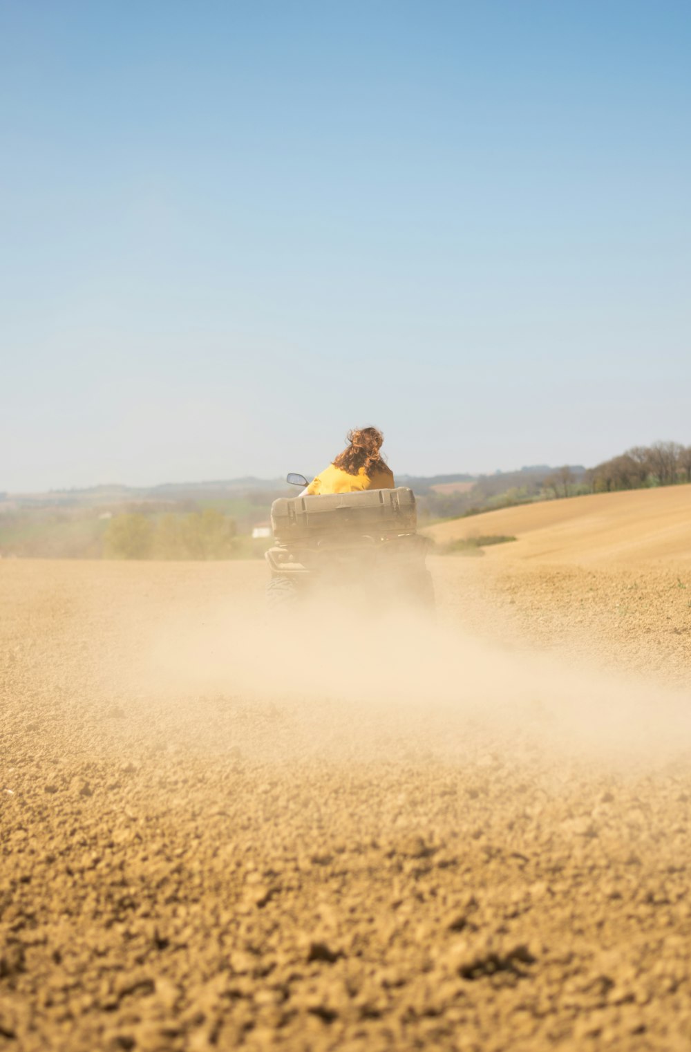 Hombre en chaqueta amarilla montando coche amarillo en campo marrón durante el día