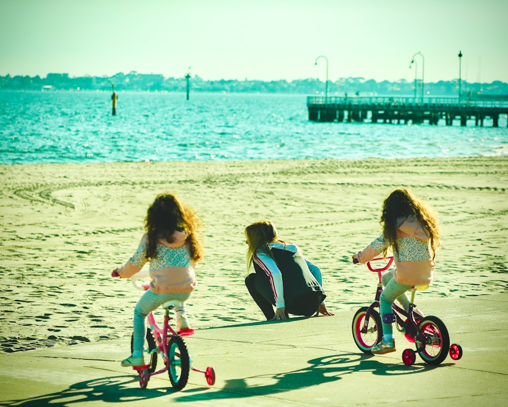 2 girls riding on bicycle on beach during daytime