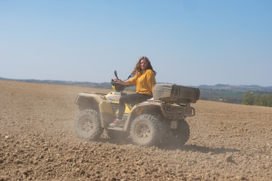 woman in brown jacket riding atv on brown field during daytime in Gers France