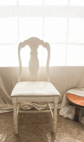 A handcrafted wooden chair with elegant curves, placed near a window.