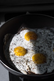 A fitness enthusiast preparing a healthy breakfast with pure brown and white eggs sizzling in a pan.