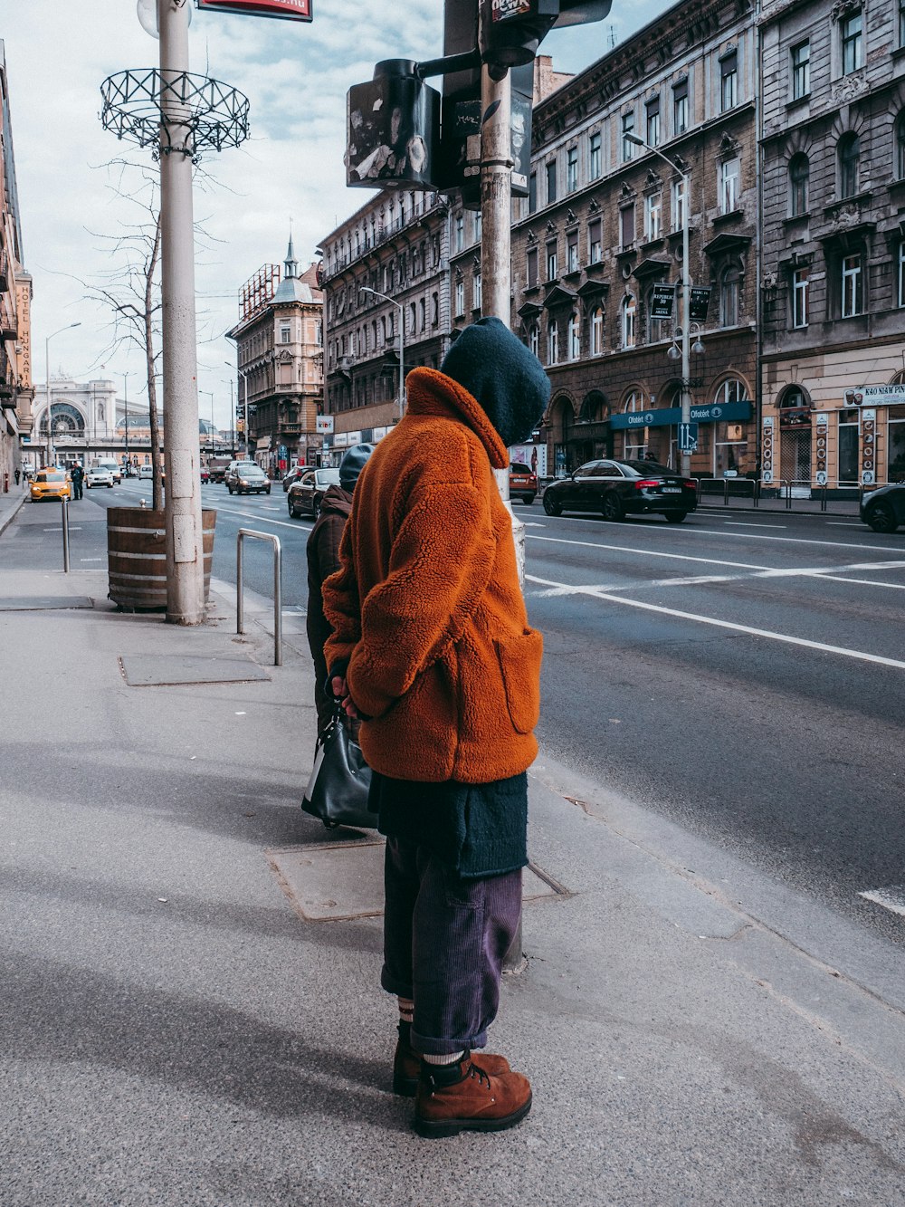 woman in brown coat standing on road during daytime