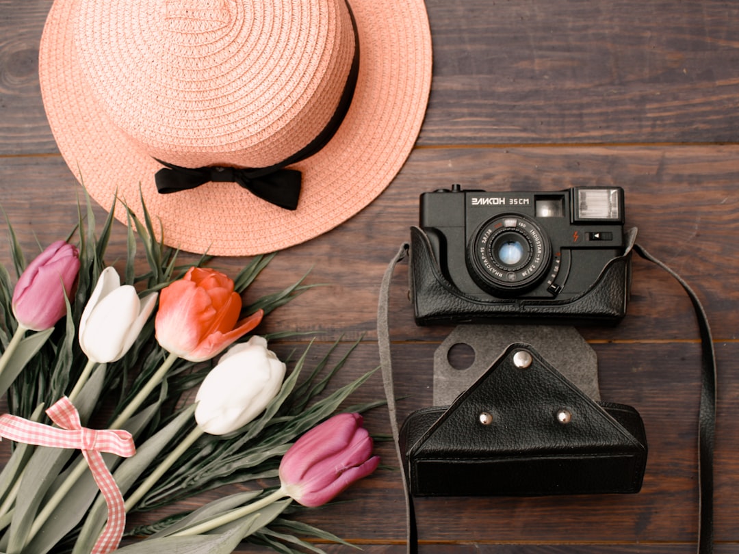 black and silver camera beside brown hat