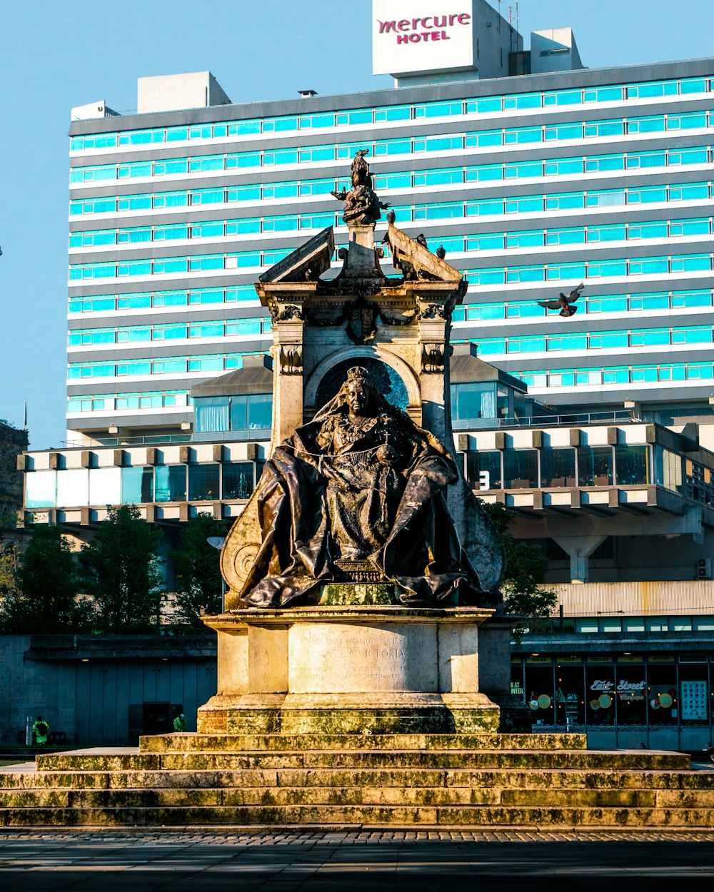 statue of man holding book near building during daytime