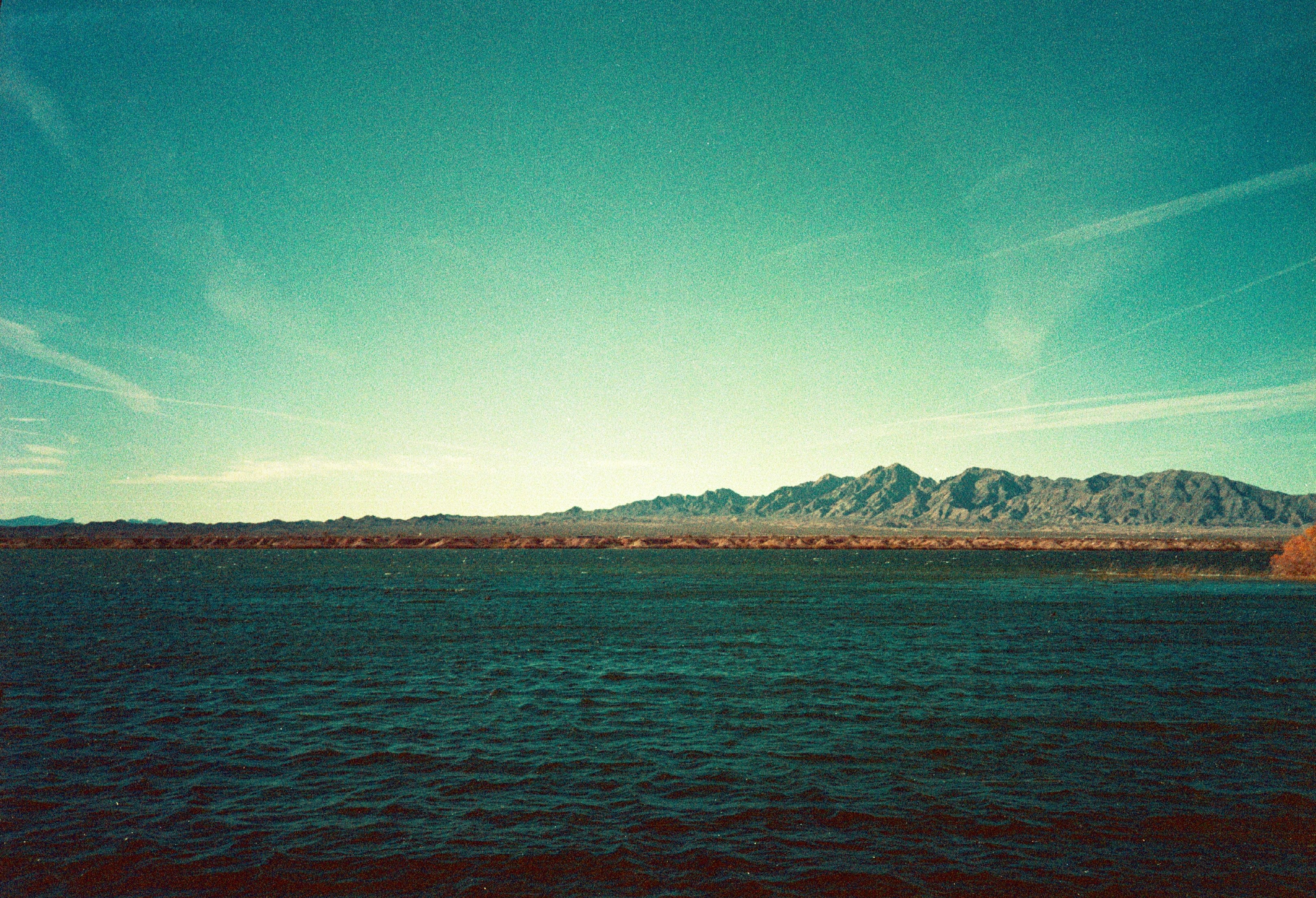 blue sea near brown mountain under blue sky during daytime