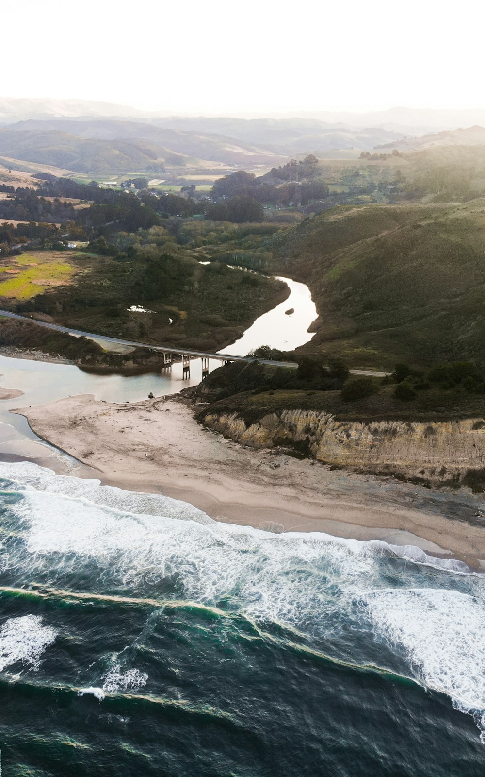 birds eye view of green and brown mountains and body of water