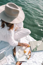 woman in white long sleeve shirt and white hat sitting on brown wooden chair