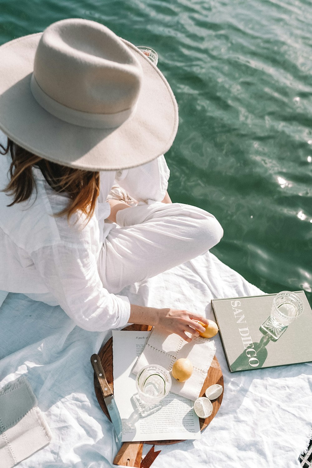 woman in white long sleeve shirt and white hat sitting on brown wooden chair