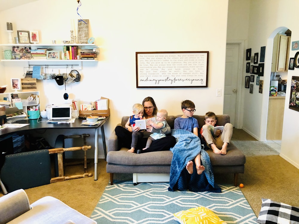 2 women and man sitting on gray sofa