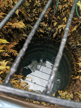 A submersible pump installed in a clear well, surrounded by lush greenery.