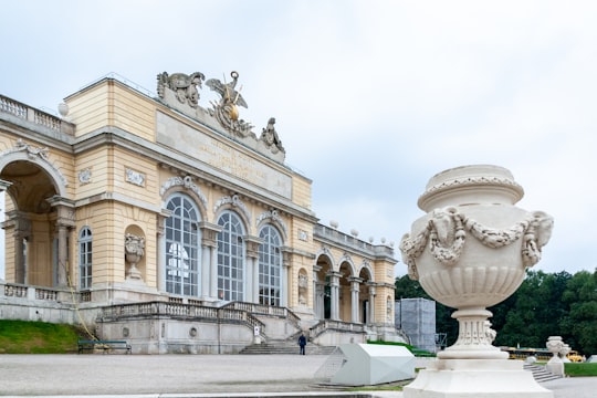 white concrete building with statues in Schönbrunner Schloss Park Austria