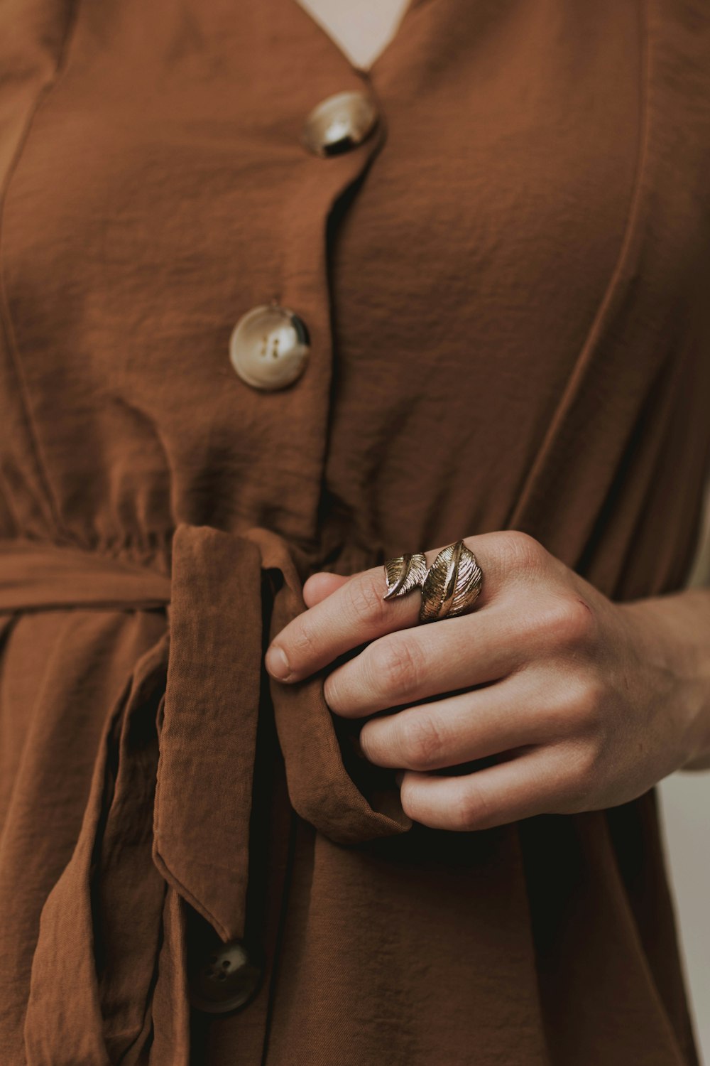 person wearing silver ring and brown button up shirt