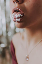 Close-up of a person placing an energy pouch on their inner lip with a bright, energetic background.