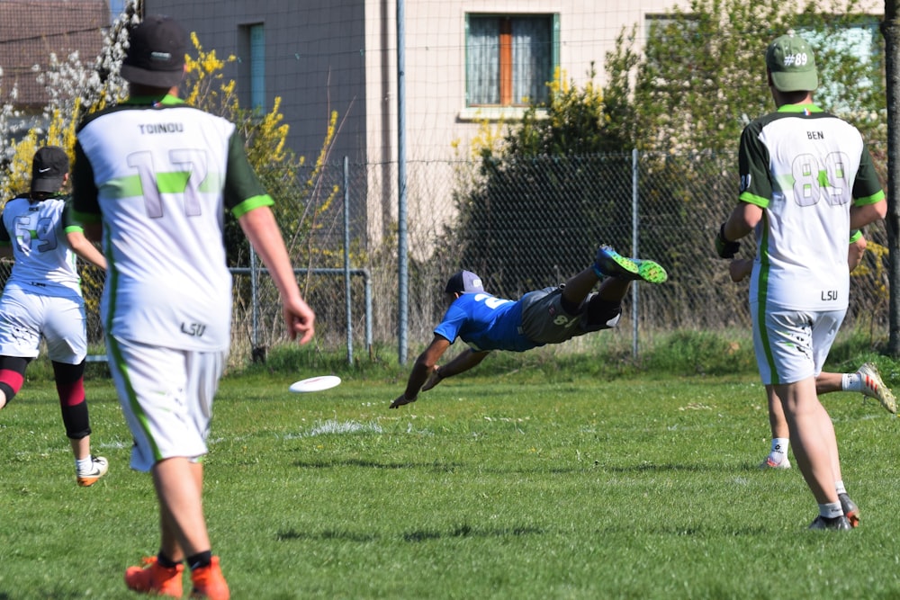 白と青のサッカージャージを着た男性が、昼間、緑の芝生のフィールドでサッカーボールを蹴る