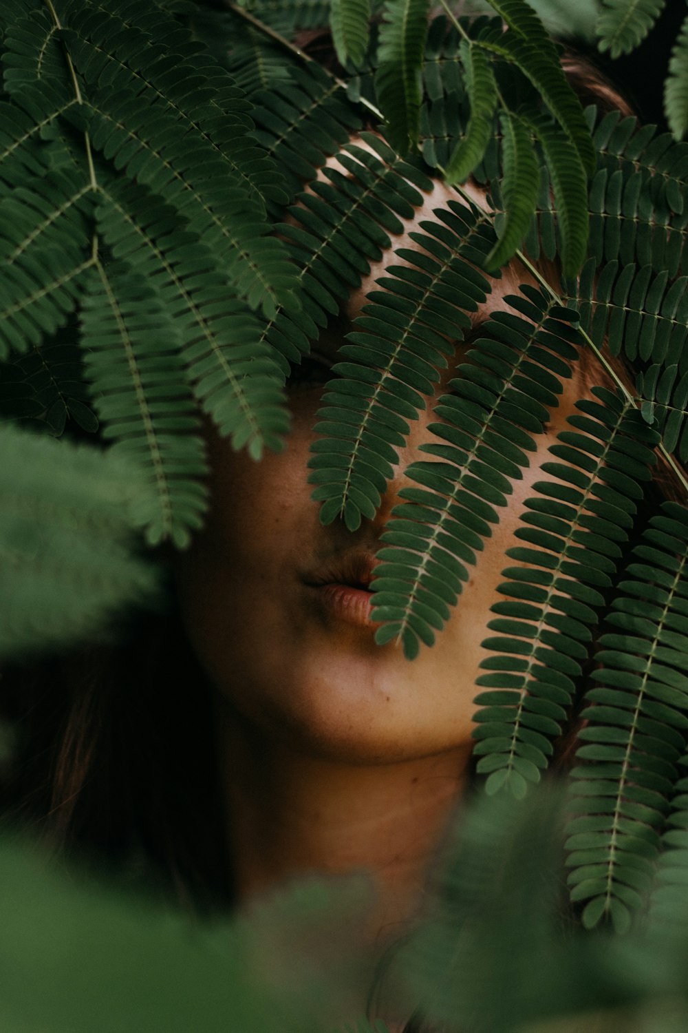 Mujer escondida detrás de hojas verdes