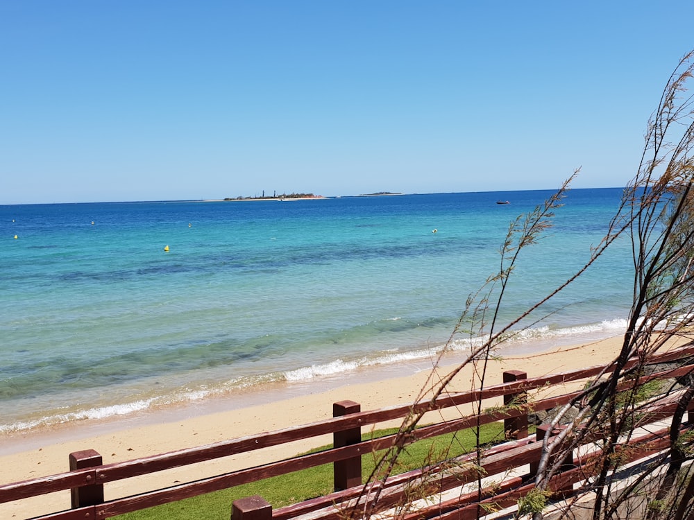 brown wooden fence near sea during daytime