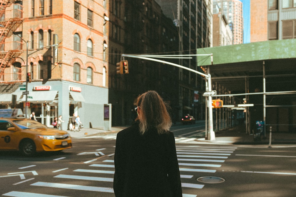 woman in black coat standing on pedestrian lane during daytime