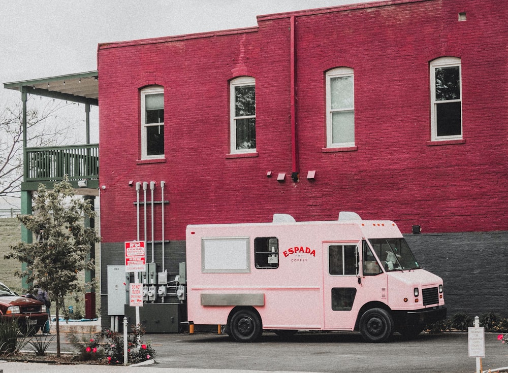 white and red van parked beside red concrete building during daytime