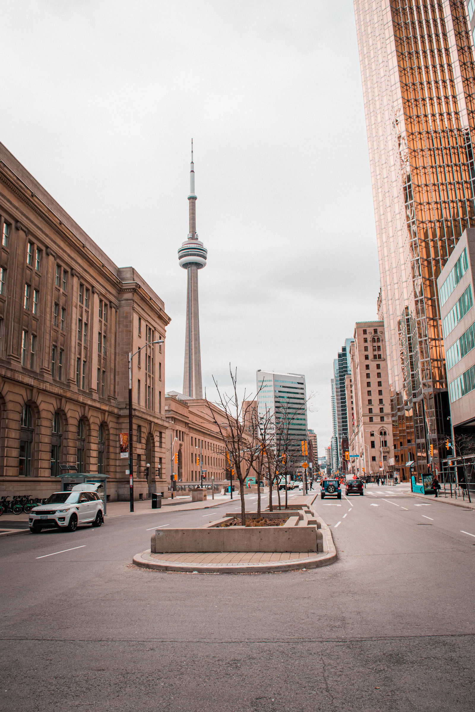 Cars parked along a sunlit downtown Toronto street beside a tall brown brick building