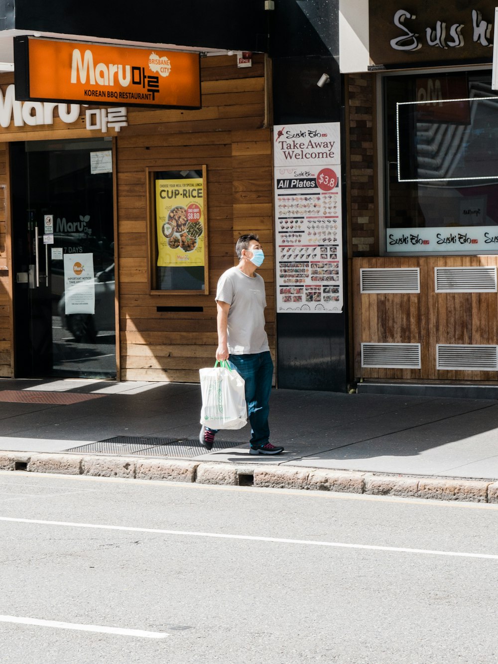 woman in white shirt and blue skirt standing on sidewalk during daytime