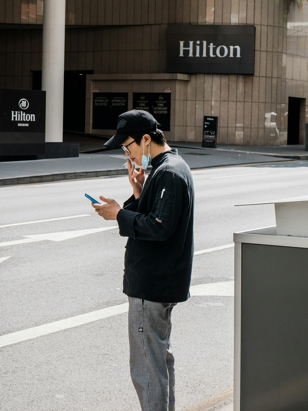 man in black long sleeve shirt and brown pants standing on gray concrete road during daytime