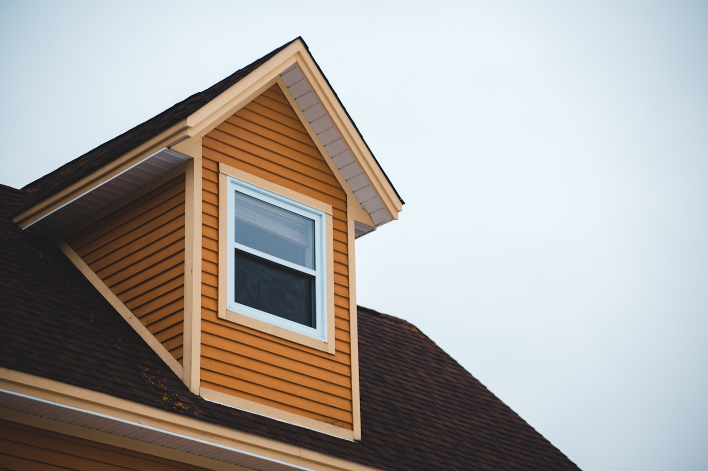 Two-story home exterior with tan horizontal lap siding installed around a dormer window