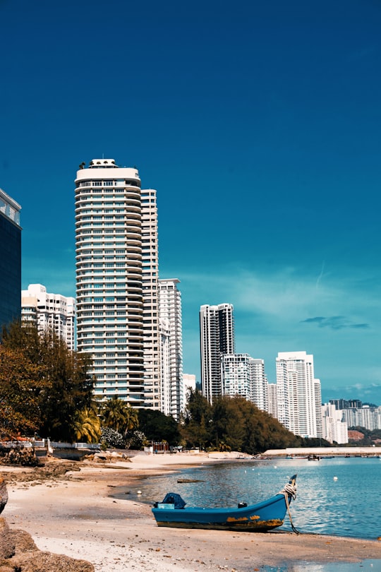 white and blue high rise buildings near green trees under blue sky during daytime in Penang Island Malaysia