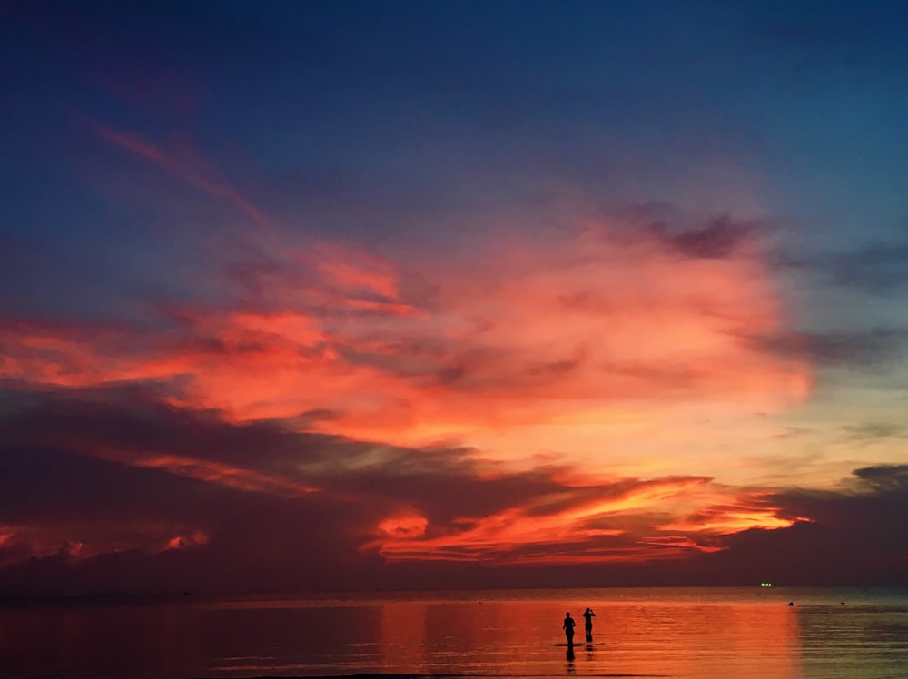 silhouette of 2 people on boat on sea during sunset