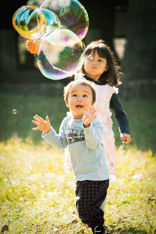 girl in white long sleeve shirt and black pants playing bubbles