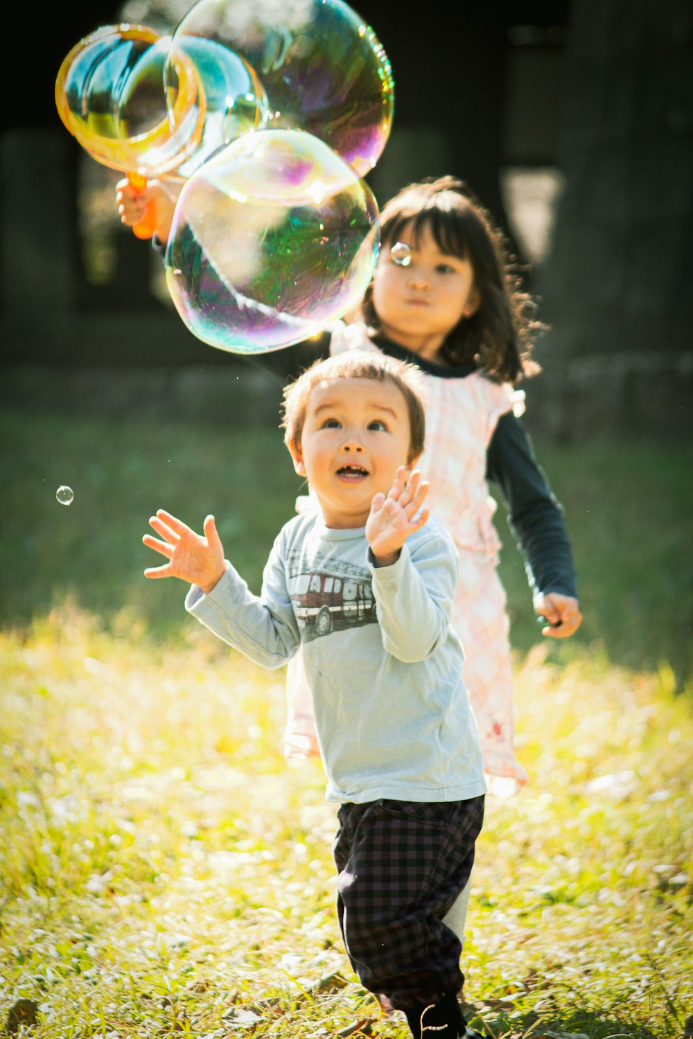 girl in white long sleeve shirt and black pants playing bubbles