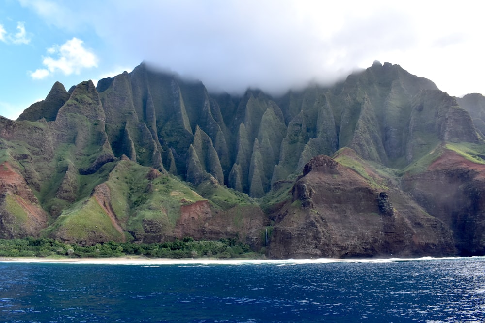 green and gray mountain beside blue sea under white sky during daytime