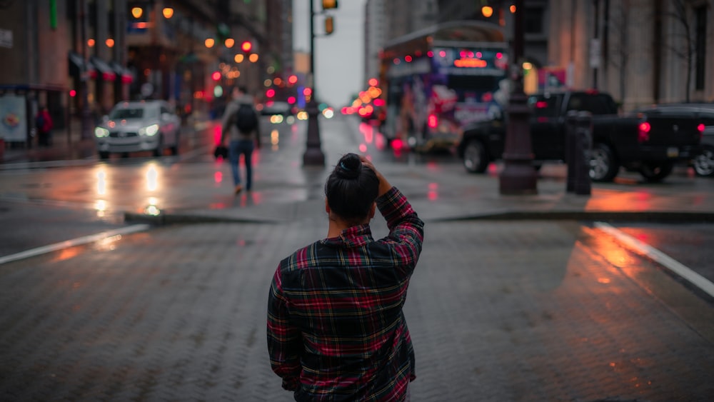 man in red and black plaid dress shirt standing on sidewalk during daytime