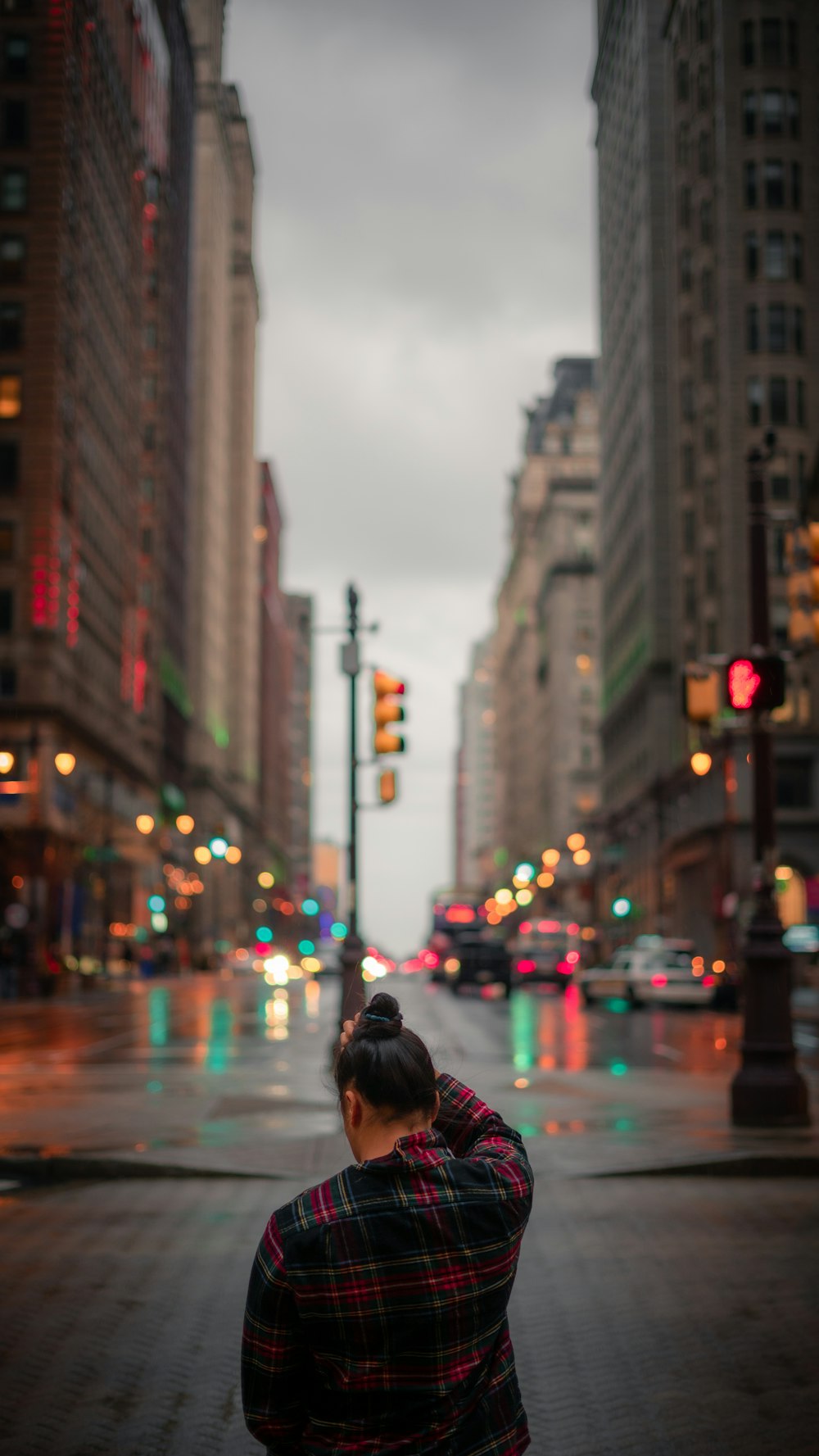 woman in red and black plaid shirt standing on sidewalk during daytime