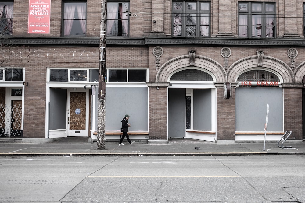 woman in black jacket walking on sidewalk during daytime