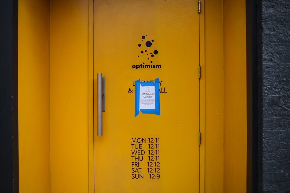 Puerta metálica amarilla con pegatina azul y blanca