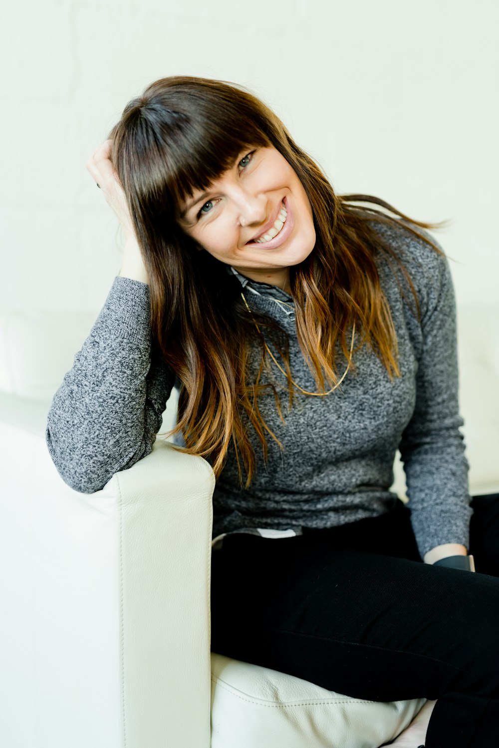 woman in gray long sleeve shirt and black pants sitting on white couch