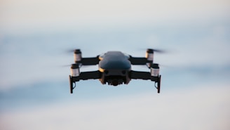 A drone in flight against a blurred sky background, capturing the sleek design and propellers in motion.