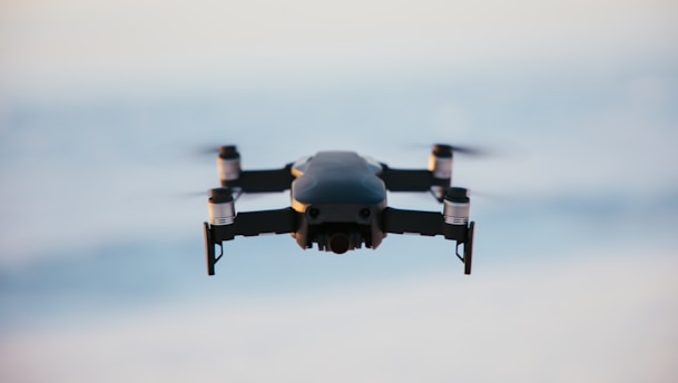 A drone in flight against a blurred sky background, capturing the sleek design and propellers in motion.