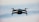 A drone in flight against a blurred sky background, capturing the sleek design and propellers in motion.
