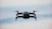 A drone in flight against a blurred sky background, capturing the sleek design and propellers in motion.