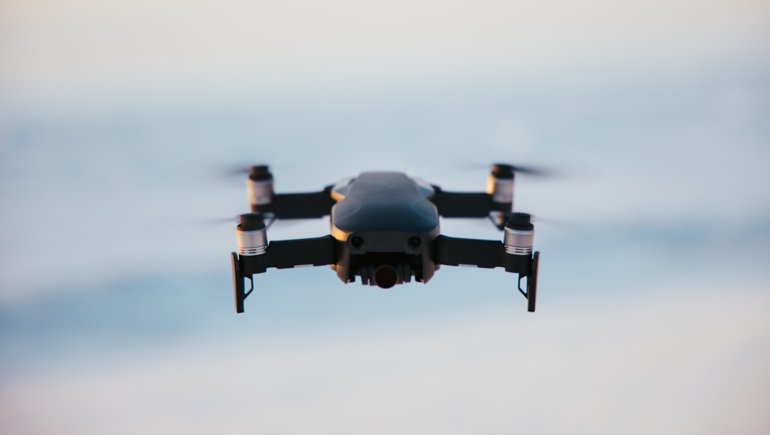 A sleek drone flying against a gradient sky background.