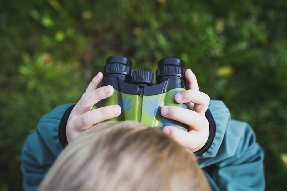 boy in green shirt holding binoculars